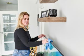 Thuiszorgmedewerker aan het afstoffen bij cliënt thuis